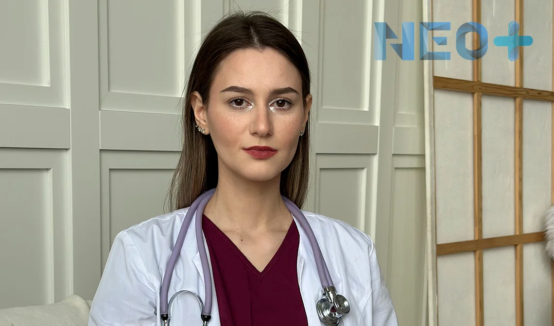 женщина врач в белом халате смотрит в камеру